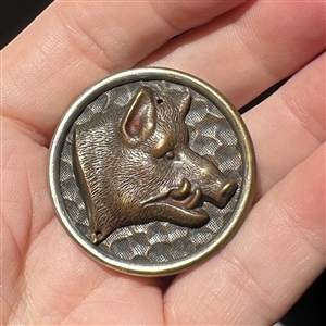 Stamped and tinted button of a boar's head.