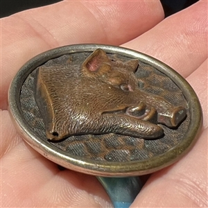 Stamped and tinted button of a boar's head.