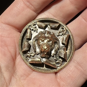 Brass button of a lion's head bursting through.