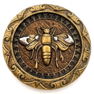 Brass button of a fabulous bee over a wood background. 