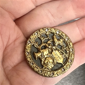 Brass button of man's head with many objects around him.