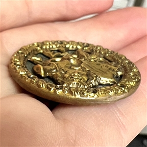 Brass button of man's head with many objects around him.