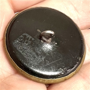 Brass button of man's head with many objects around him.