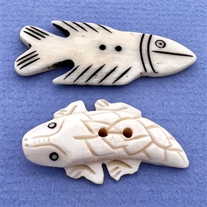 Two carved natural material buttons of a fish and a lizard.