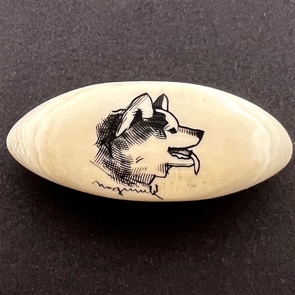 Scrimshaw button of a husky dog on natural material