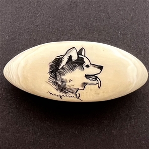 Scrimshaw button of a husky dog on natural material