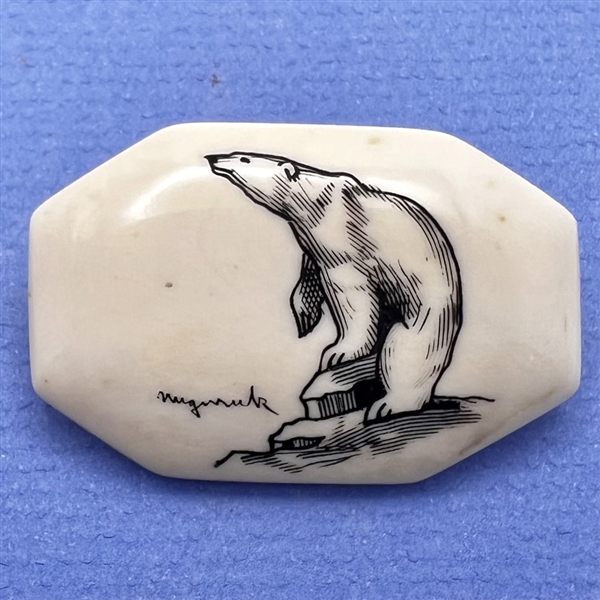 Scrimshaw button of a polar bear on natural material