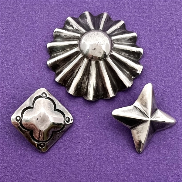 Three sculptural Native American silver buttons of assorted shapes.