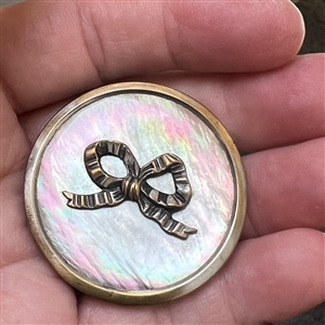 A 19th c. Iridescent pearl button with silvered brass bow.