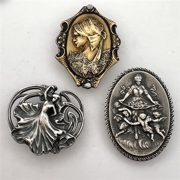 Three stamped metal buttons of women.