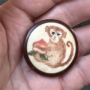 Natural material button of a monkey with a turnip set in boxwood.