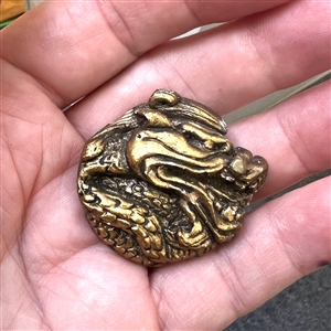 Painted plaster button of a dragon head.