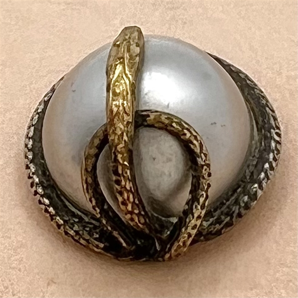 Snake entwined around pearlized glass dome mounted in metal button.