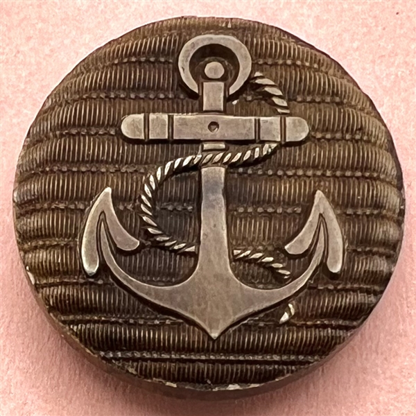 Composition button of anchor with fouled rope - imitation fabric background.