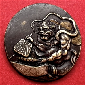 Japanese metal work button of a masked character with a fan. 