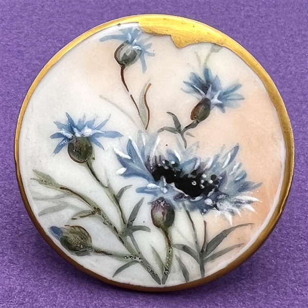 Painted porcelain button of blue cornflowers.