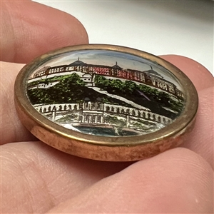 Reverse painted under glass button of an architectural scene of a large building.