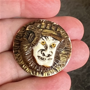 Carved natural material button of an Asian warrior.