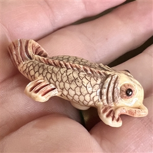 Carved natural material button of a realistic Koi fish.