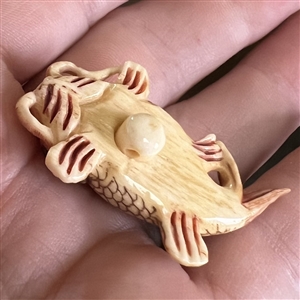 Carved natural material button of a realistic Koi fish.