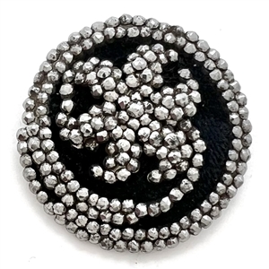 Facetted cut steel button of lily flower with velvet background.