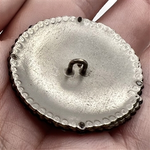 Facetted cut steel button of lily flower with velvet background.