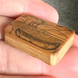 Wood studio pyrography button of a canoe and water scene.