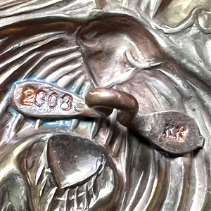 Stamped brass studio button of “Trixie by Kevin Kinne.