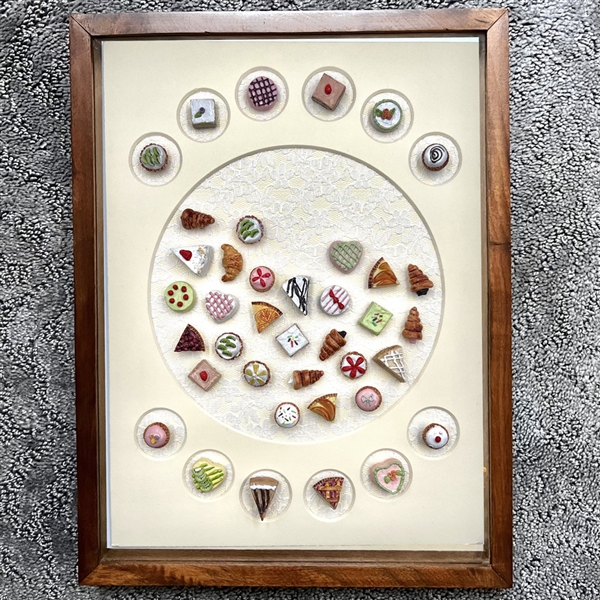 Framed card of 39 molded plastic buttons of pastries and deserts.