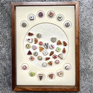 Framed card of 39 molded plastic buttons of pastries and deserts.