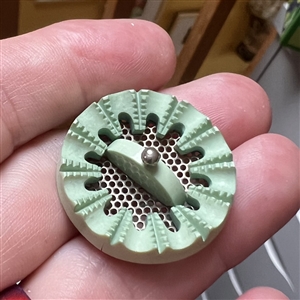 Screen back sculptural casein button with pin shank.
