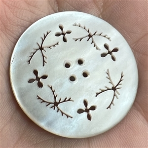 A 19th c. 4-hole pearl button of incised and pierced plant life.