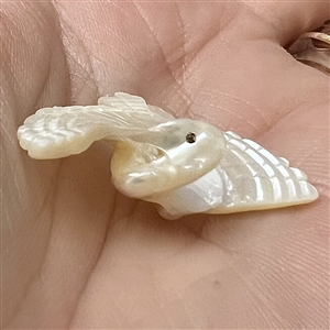 Carved pearl button of a realistic flying crane.