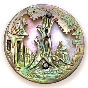 United carved abalone over lavender color shell button of a landscape scene.