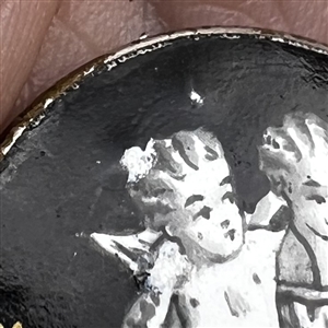 “En Grisaille enamel on black background with gold accents of cherub and child.