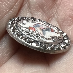 Enamel on white metal button of a woman in hat with border of faceted cut-steels.