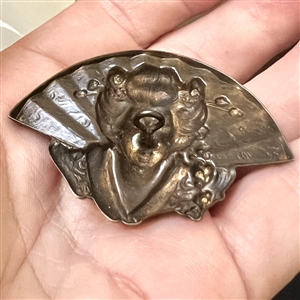 Stamped brass in high relief button of a realistic fan behind a Asian woman.