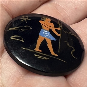 Painted casein button of an Egyptian man with symbols. 