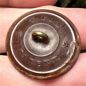 Transparent dyed horn sporting button of a whippet.