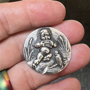 Silver button of Putto piping to a bird.