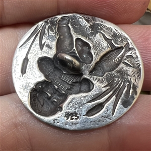 Silver button of Putto piping to a bird.