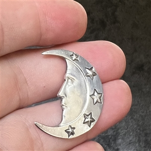 Silver button of man in the moon crescent face and stars.