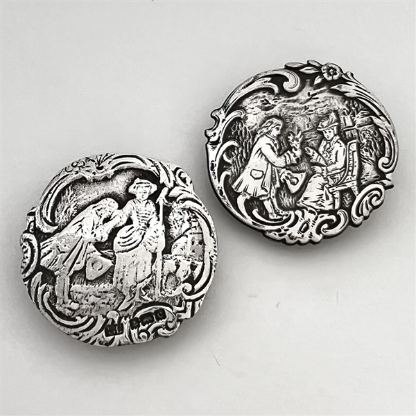Two silver buttons of courting couples.