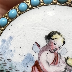 “Cherub with a Bird painted enamel button with encrusted blue enamel border.