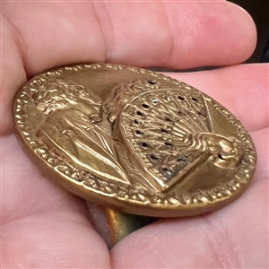 Stamped brass button of “The Stolen Kiss.