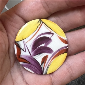 Painted porcelain button of an abstraction of a window with plant life.