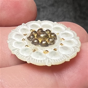 A medium size 18th c. Carved pearl button with gilded metal center.