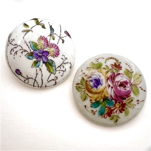 Two painted porcelain buttons of flowers.