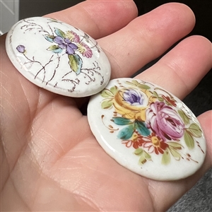 Two painted porcelain buttons of flowers.