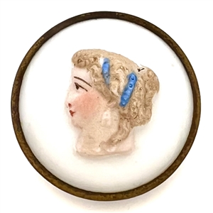 Painted glass button of a womans head set in metal.